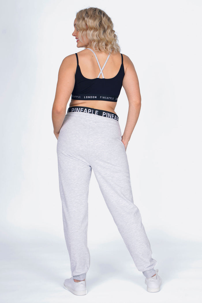 Woman wearing Grey Double Band Joggers and Black Bra Top, back view