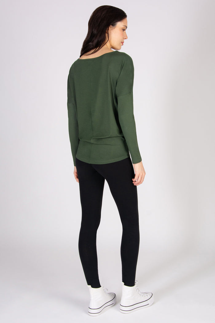 Woman wearing a long sleeve top and black leggings on a white background