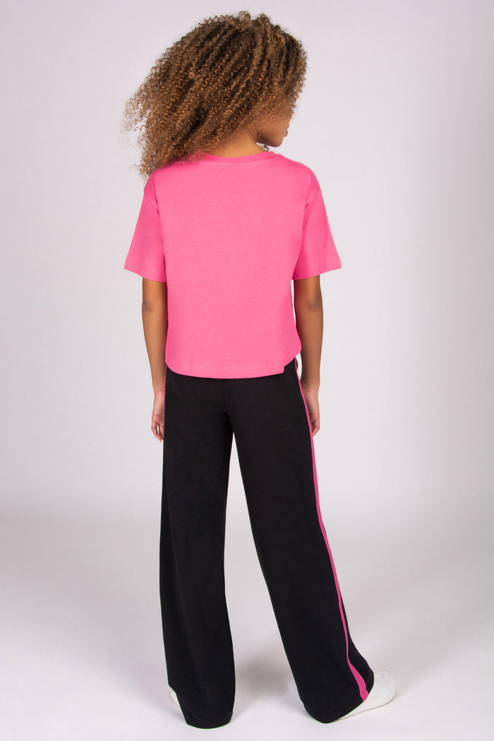 Person wearing a pink t-shirt and black trousers with pink stripe on a white background