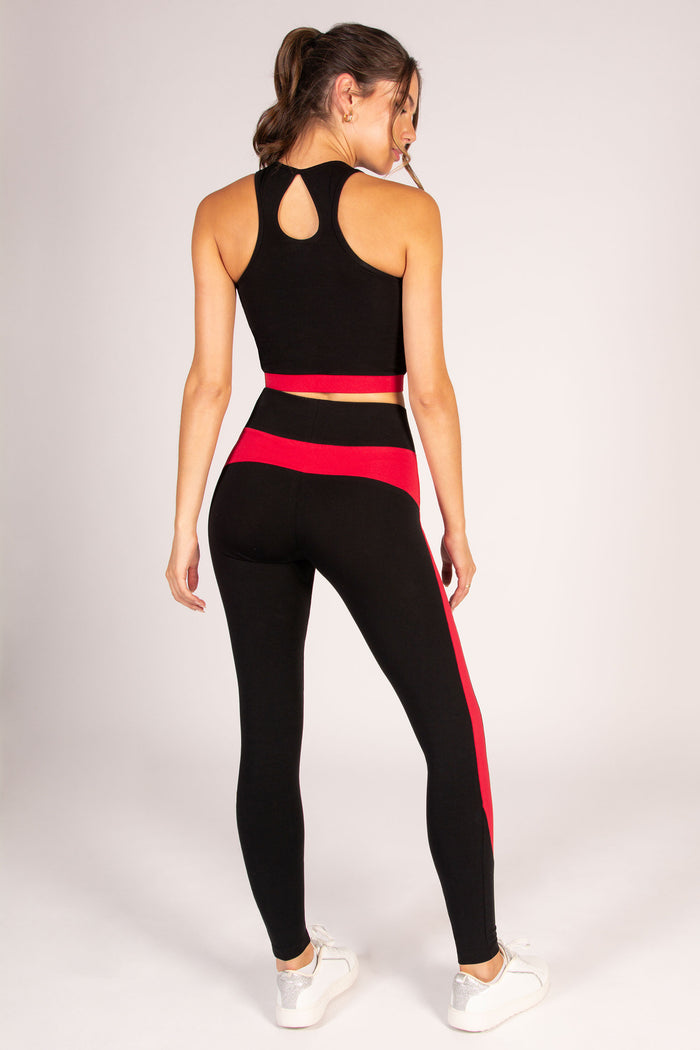Women's black and red yoga outfit, featuring a mid length crop top and high waisted leggings.