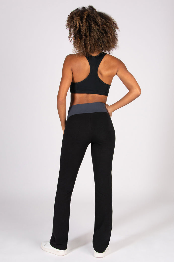 Person wearing a black sports bra and flared bootcut trousers on a white background
