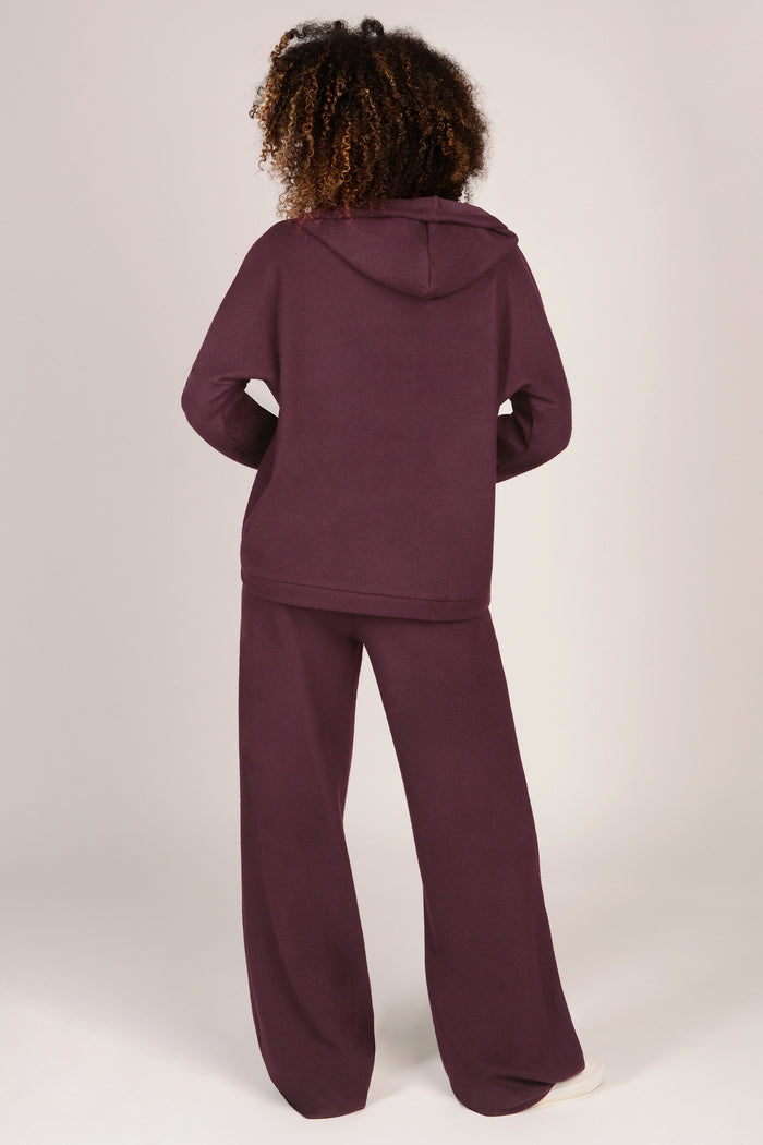 Person wearing a maroon tracksuit on a white background