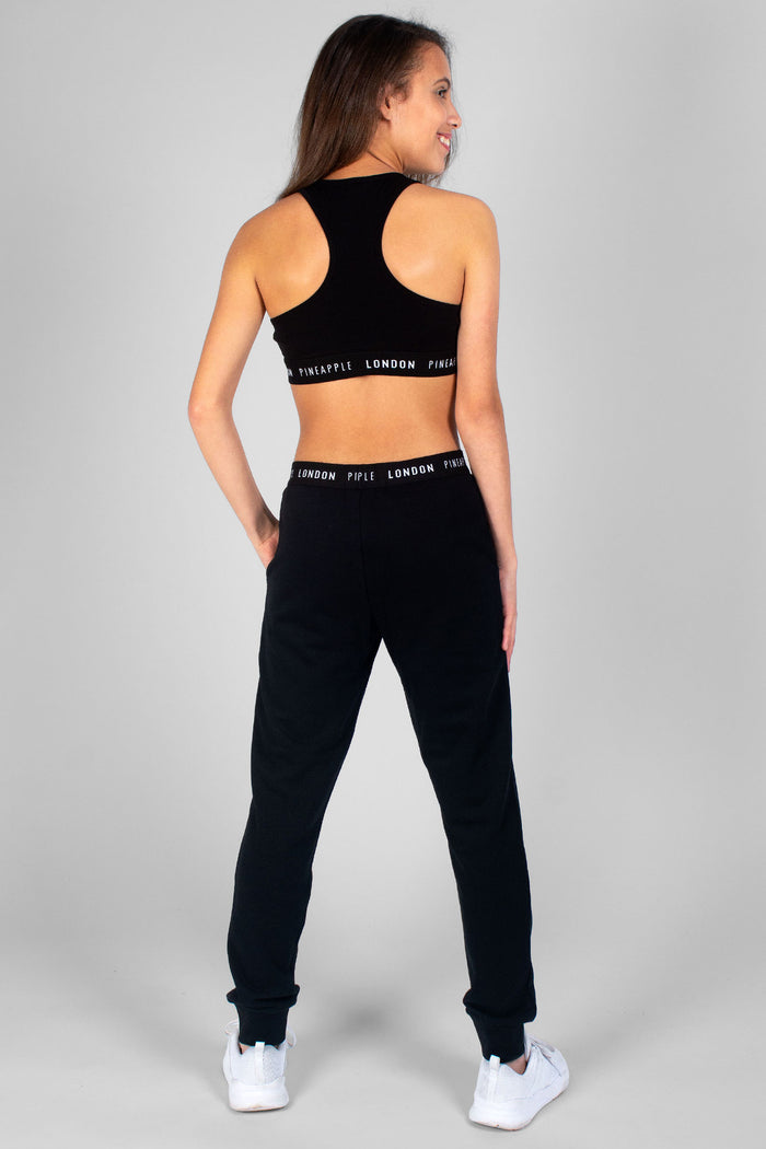 Girl wearing black Script Crop Top with print logo hem and matching black joggers