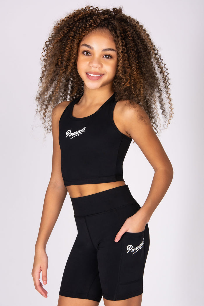 Girl wearing a black sports vest with shorts on a white background