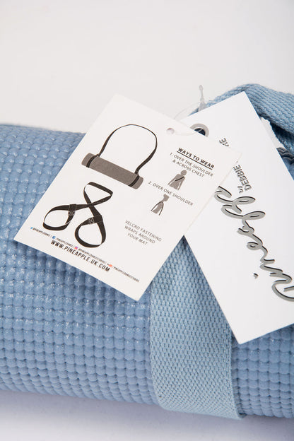 Pale blue yoga mat with matching straps to carry on the shoulders