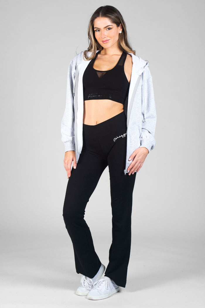 Woman wearing black Bootcut Jersey Trousers with  black cropped vest and grey hoodie