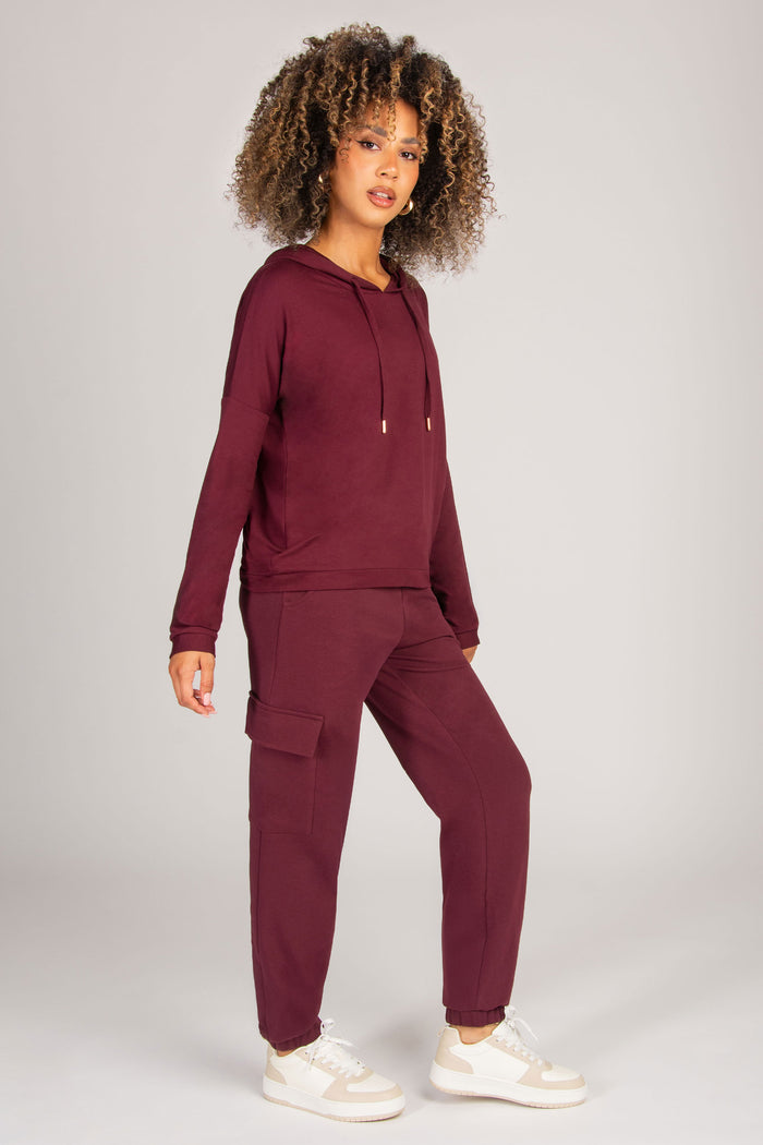Woman wearing a burgundy tracksuit on a plain background