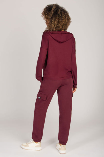 Woman wearing a burgundy tracksuit on a white background