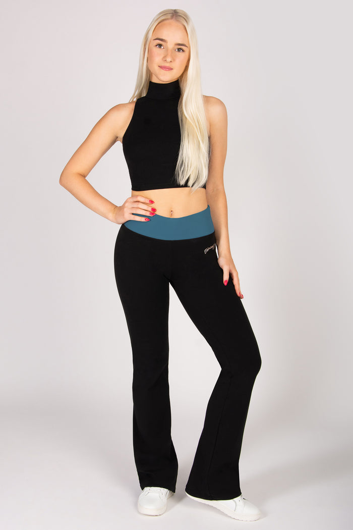 Woman wearing a black sleeveless top and black flared pants on a white background