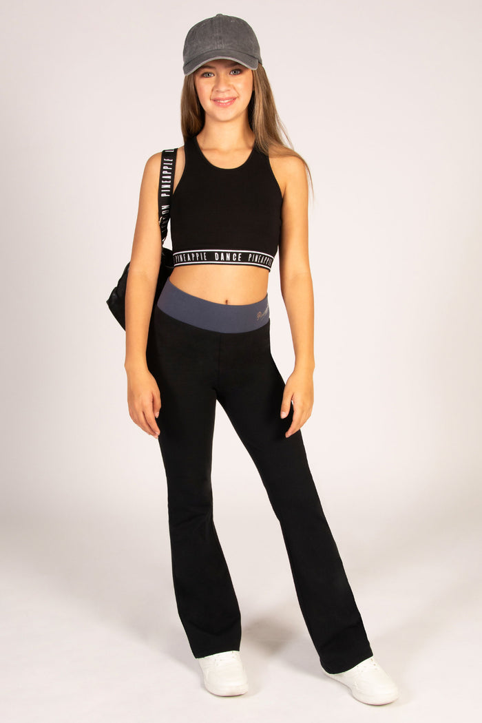 Teen's flared leggings in black with wide elasticated waistband in dark grey colour and small silver foil Pineapple Dance Studios branding.