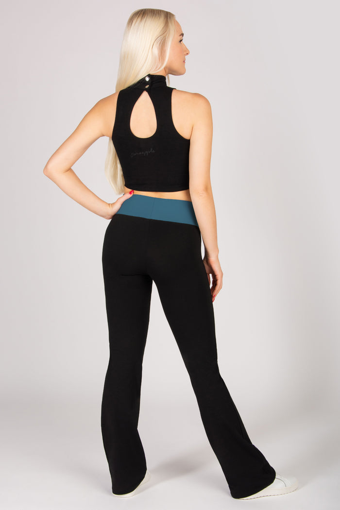 Woman wearing a black crop top and black flared yoga pants on a white background