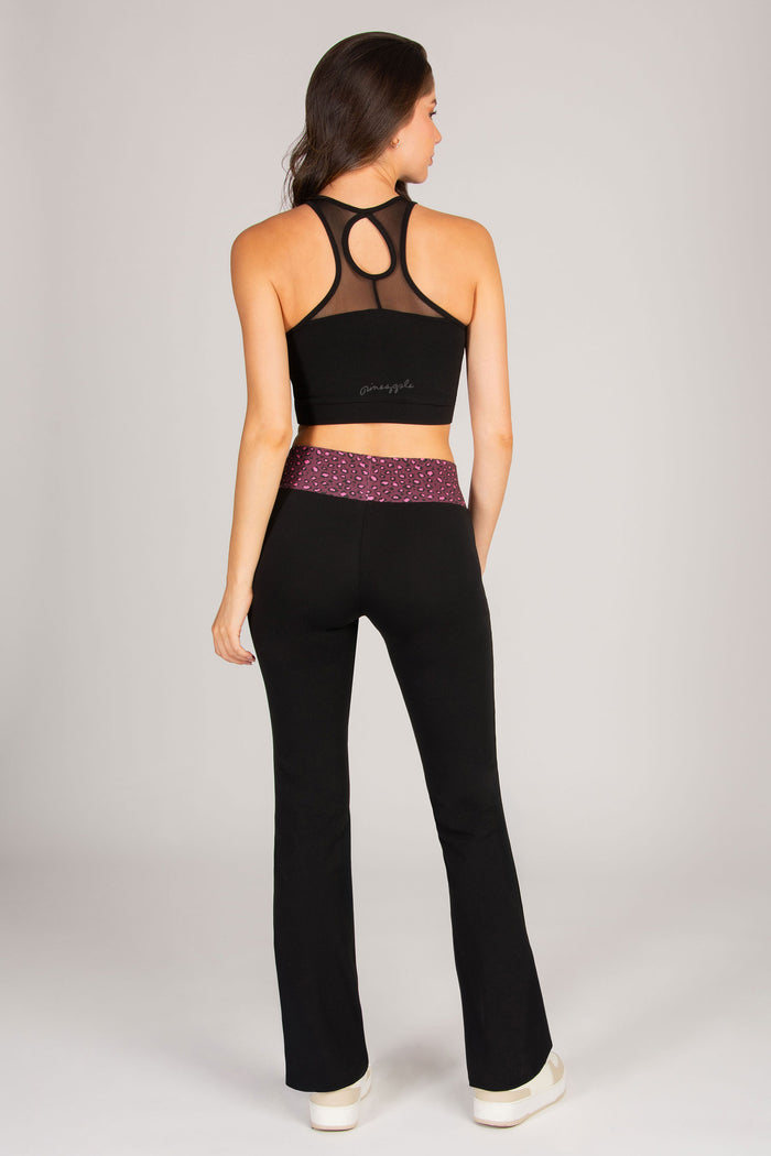 Woman wearing a black sports bra and flared leggings with maroon leopard waistband