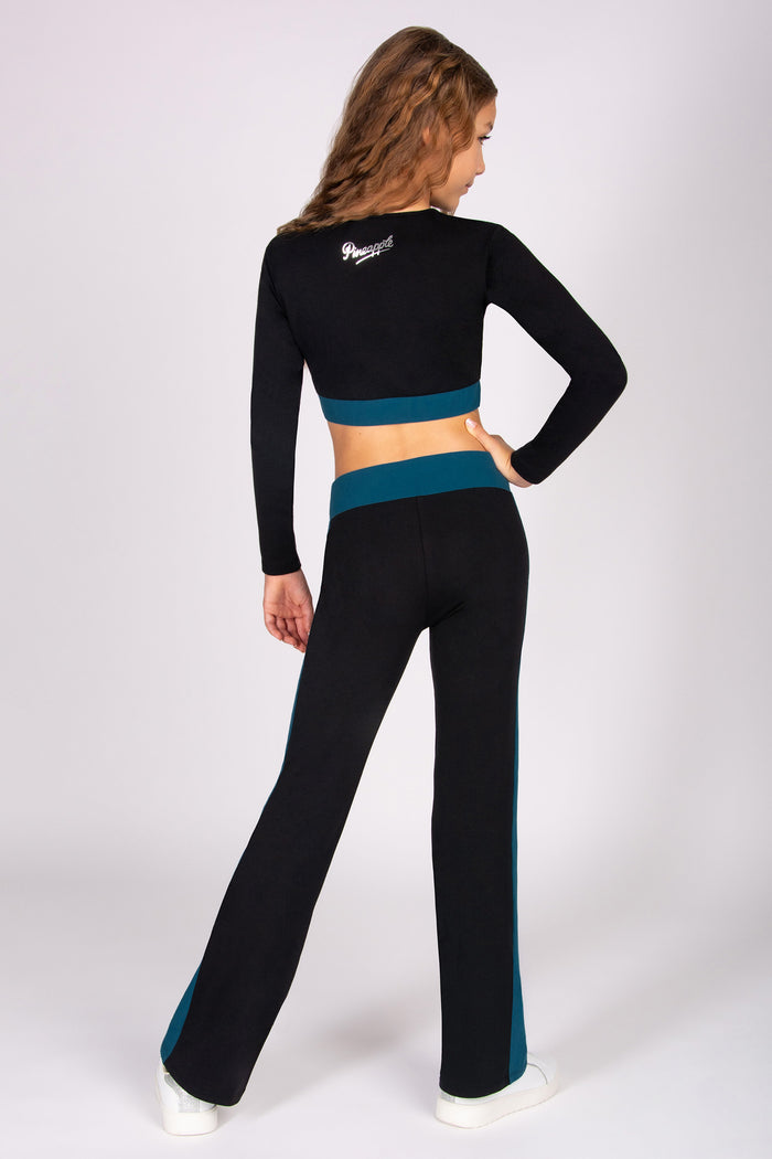 Girl wearing a black and teal athletic outfit on a white background