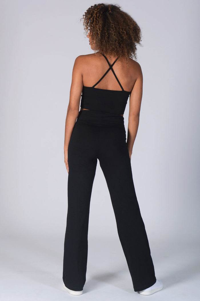 Woman wearing black Fold Down Waist Jersey Trousers and black vest with crossover straps.