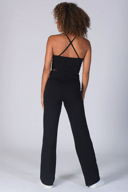 Woman wearing black Fold Down Waist Jersey Trousers and black vest with crossover straps.