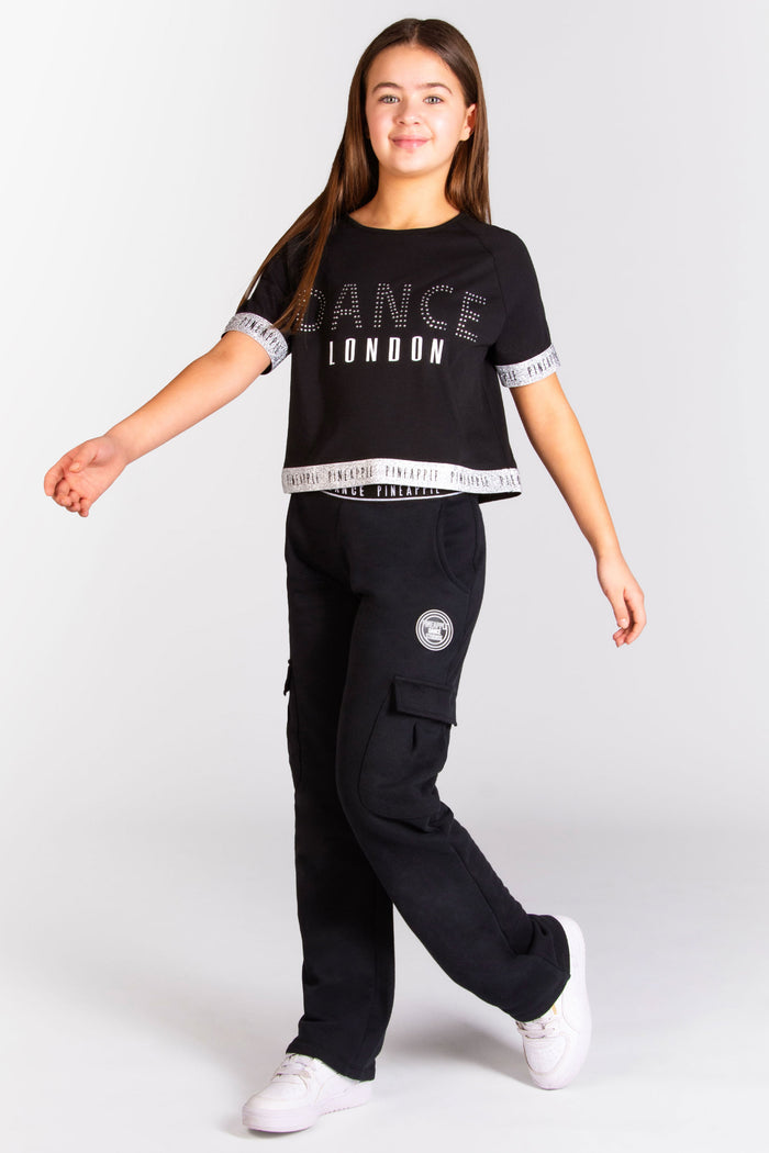 Girls' black crop top with Pineapple Dance Studios branding and silver glitter tape detail
