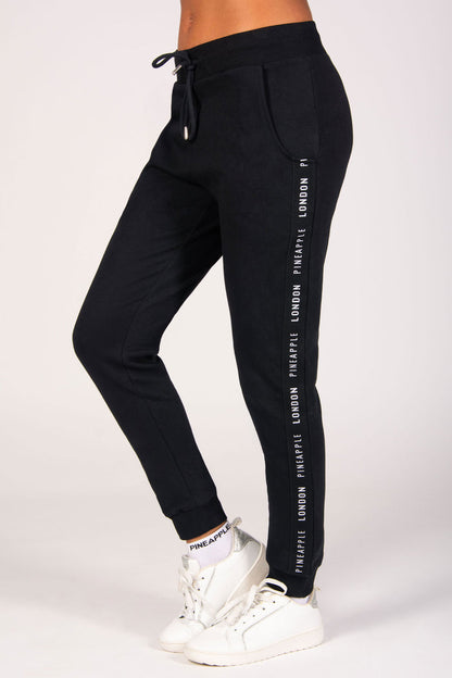 Women's black jacquard tape joggers with two side pockets, elasticated waistband and cuffs, and adjustable drawcords for a personalised fit.