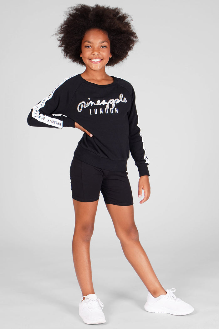 Girl wearing Jacquard Sweat Topwith contrast logo and black cycling shorts