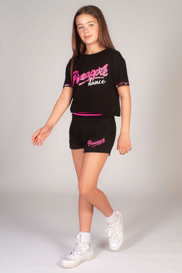 Kids' black logo dance crop top with Pineapple Dance chest print and dance print along the sleeves.