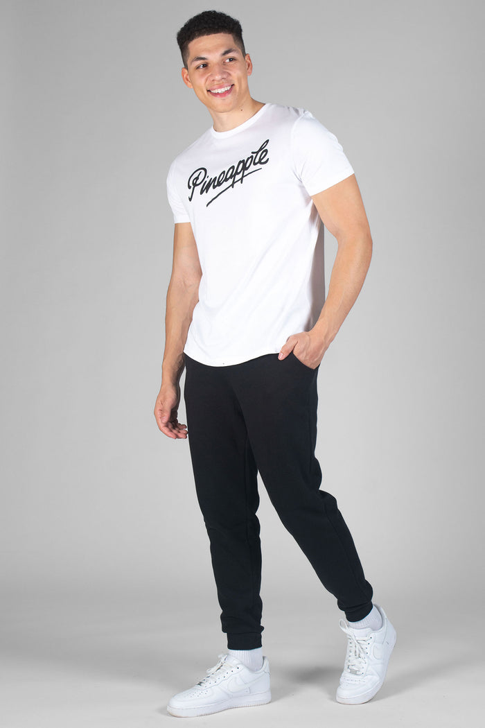 Man wearing white T-Shirt with logo and black jogging trousers with pockets