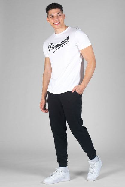 Man wearing white T-Shirt with logo and black jogging trousers with pockets