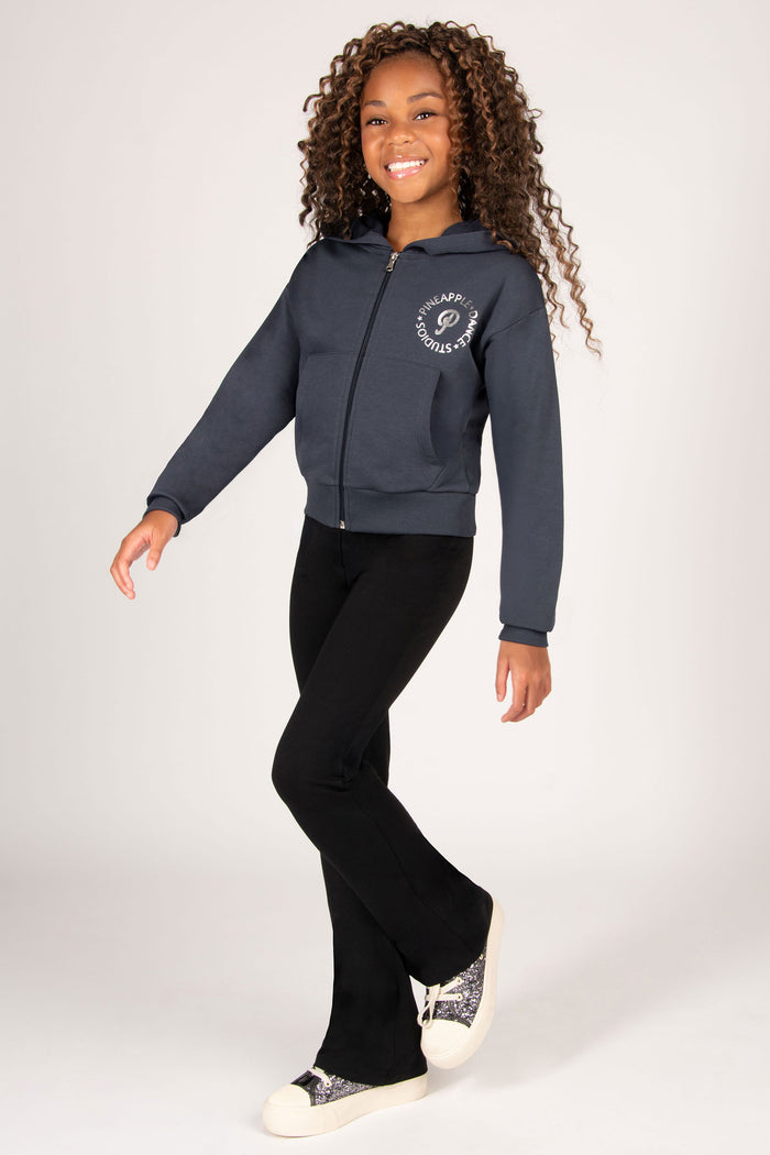 Child wearing a dark grey zip hoodie with pockets and black flared pants on a white background