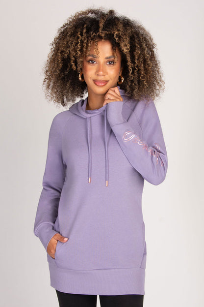 Woman wearing a light purple hoodie with decorative sleeves on a plain background