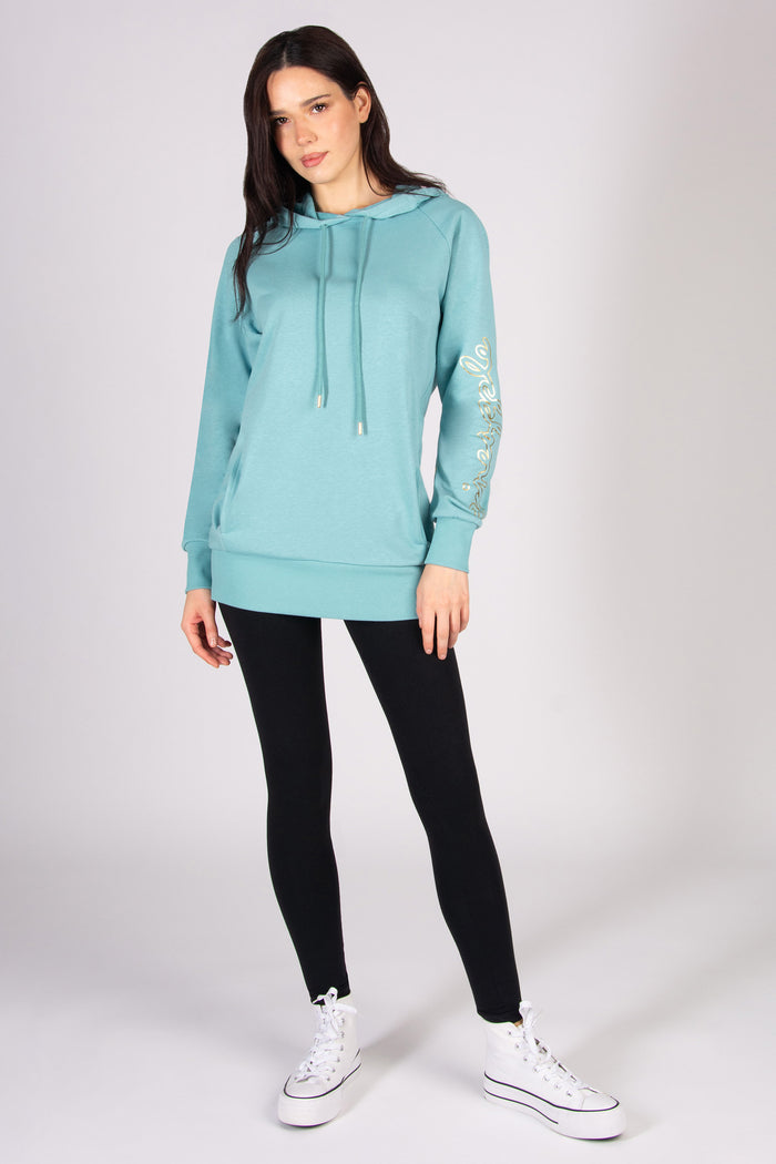 Woman wearing a light blue longline hoodie and black leggings against a plain background
