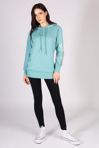 Woman wearing a light blue longline hoodie and black leggings against a plain background