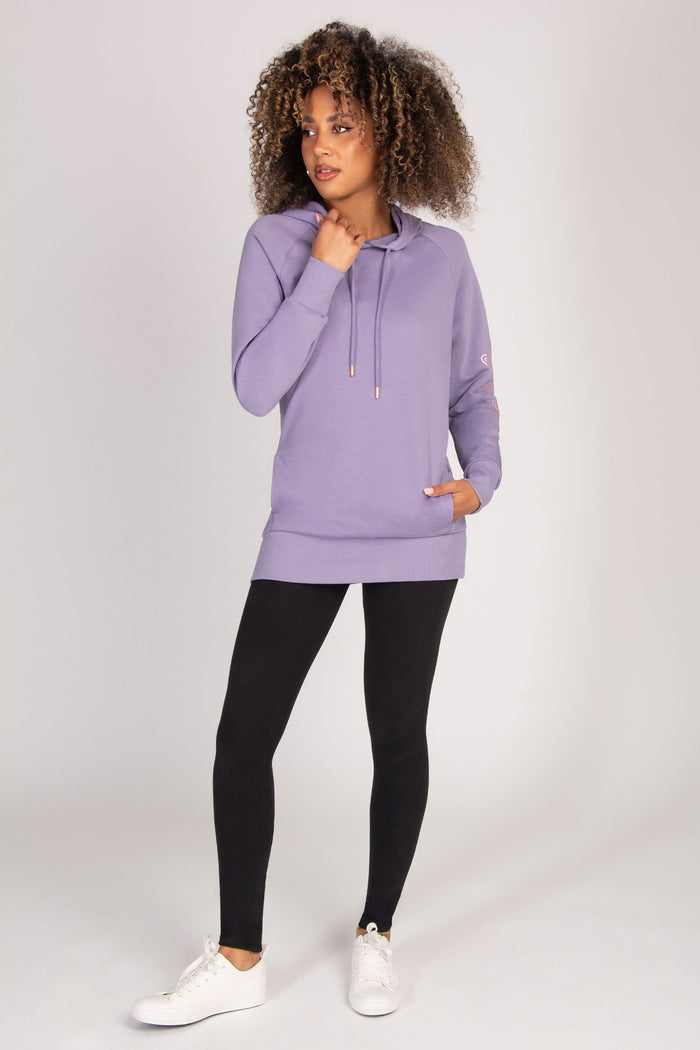 Woman wearing a purple hoodie and black leggings on a white background