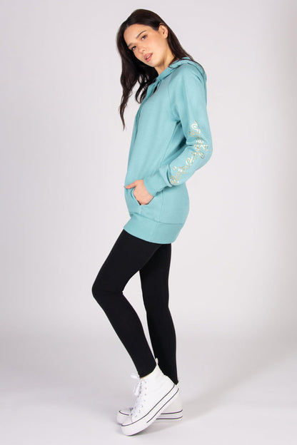 Woman wearing a light blue longline hoodie and black leggings against a plain background