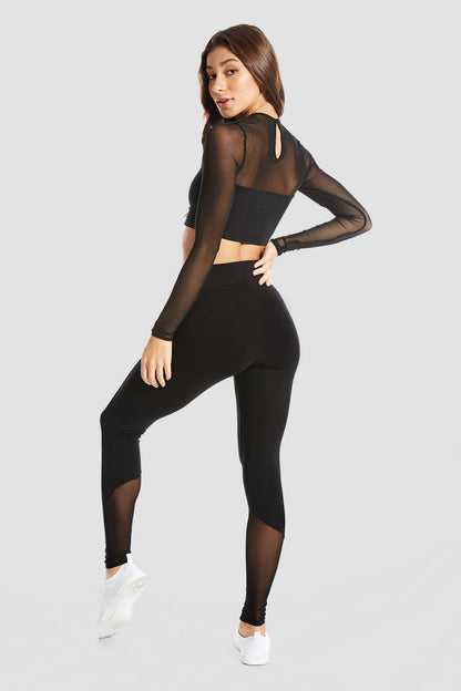 Woman wearing Black Monroe Long Sleeve Crop Top with mesh sleeves and black leggings