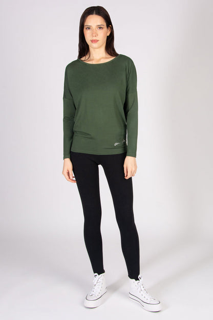 Woman wearing a khaki long-sleeve top and black leggings on a white background