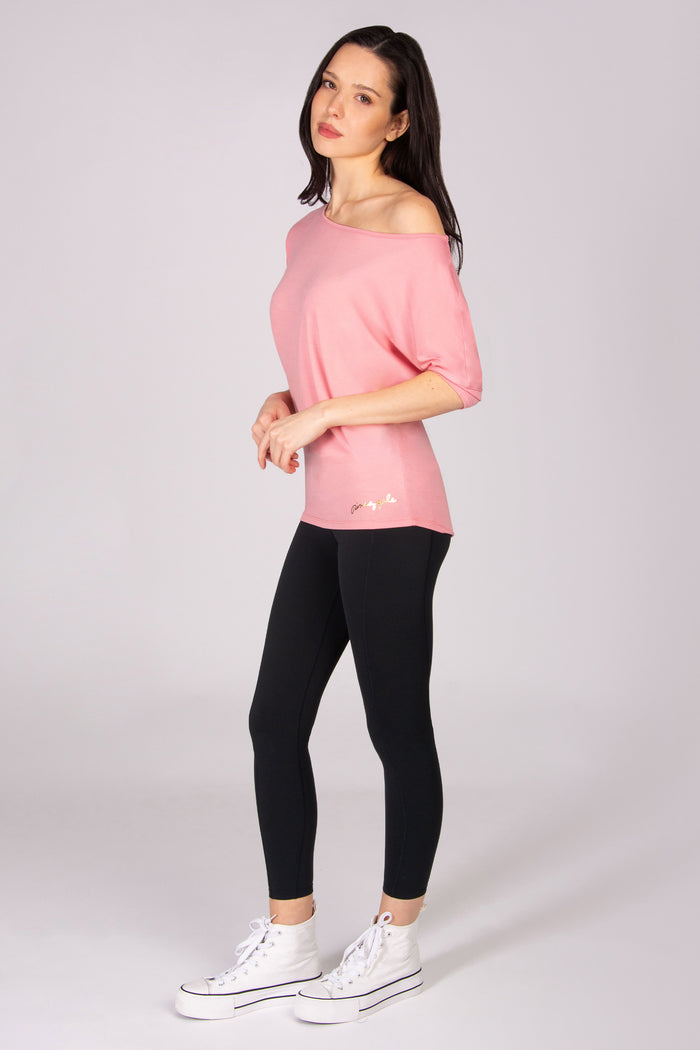 Woman wearing a pink short sleeve top and black leggings on a white background