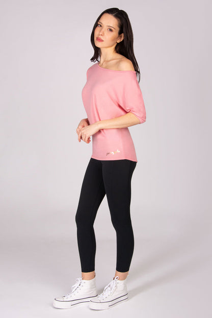 Woman wearing a pink short sleeve top and black leggings on a white background