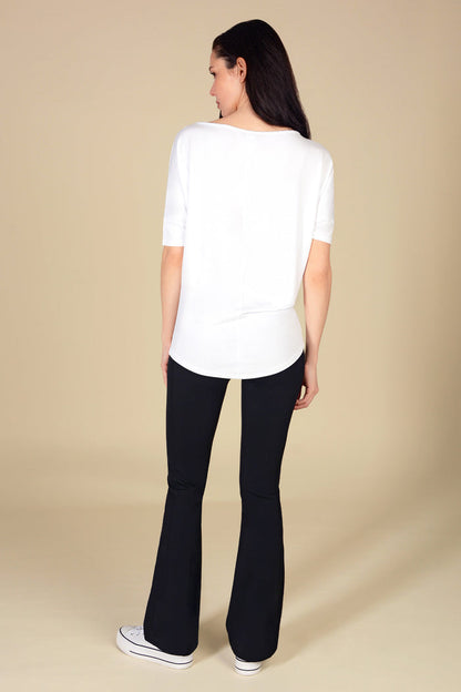 Woman wearing a white top and black flares on a beige background