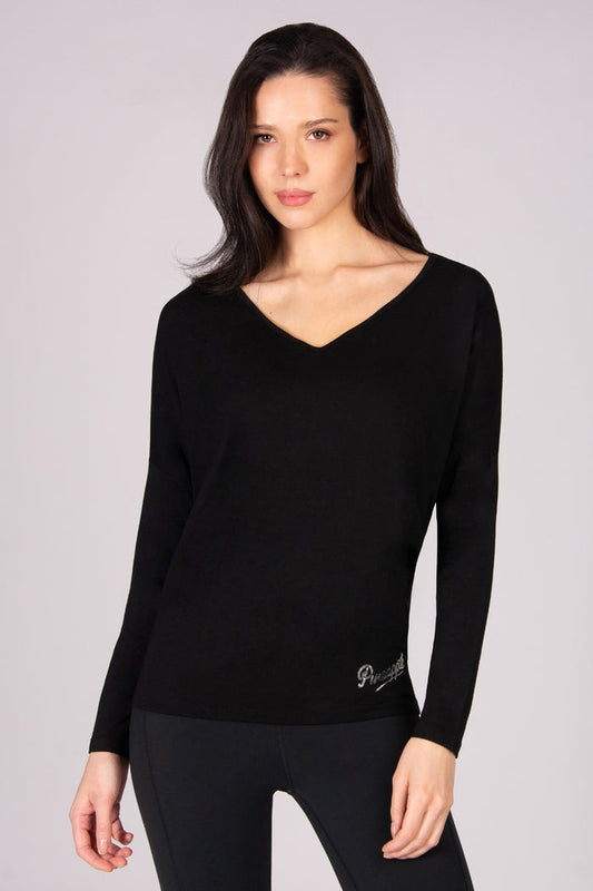 Woman wearing a black long-sleeve top with a v neck on a grey background