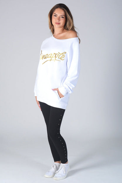 Woman wearing long sleeve white Monster Sweater with gold Glitter logo and studded black leggings