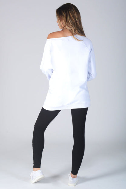 Woman wearing off the shoulder white Monster Sweater and black leggings