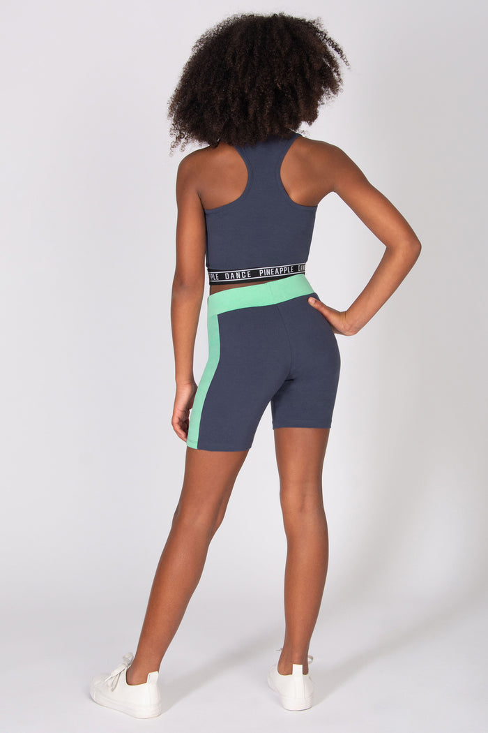 Girls wearing dark grey cycling shorts with mint green side panels and contrast waistband with matching sports top on a grey background