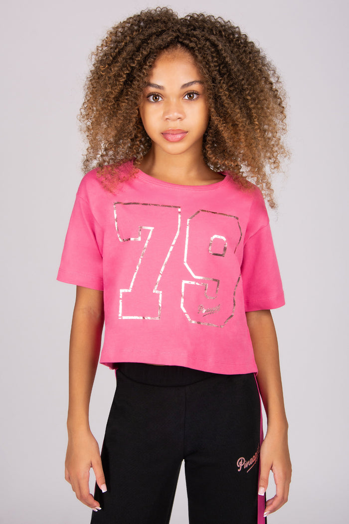 Person wearing a pink t-shirt with the number 79 and black pants on a plain background