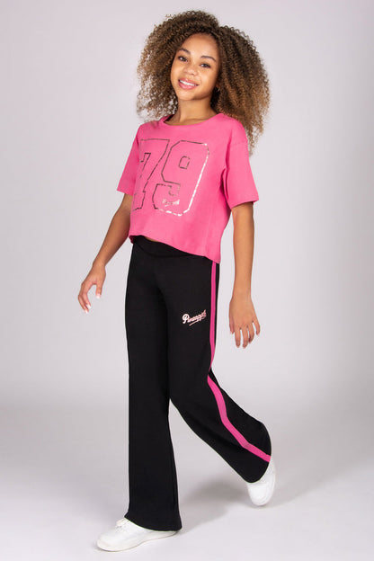 Person wearing a pink t-shirt with the number 79 and black trousers with pink paneling on a white background
