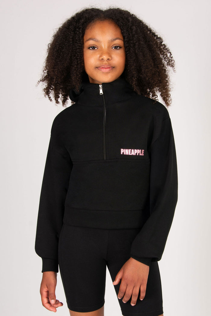 Child wearing a black half-zip sweatshirt with 'Pineapple' logo on a white background