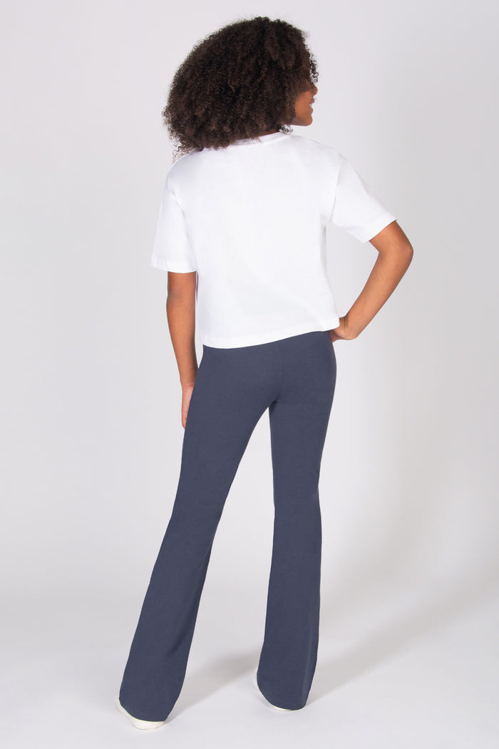 Girl wearing a white shirt and dark grey pants on a white background