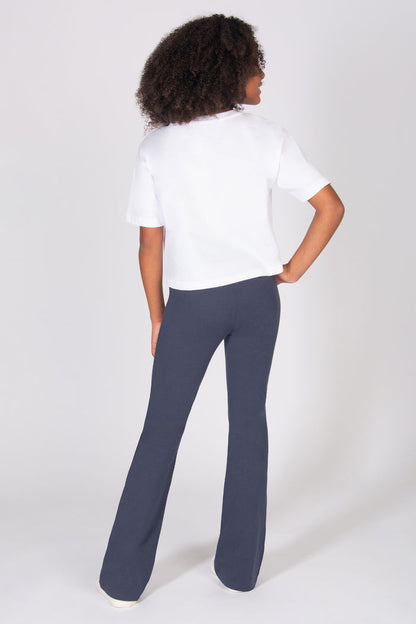 Girl wearing a white shirt and dark grey pants on a white background