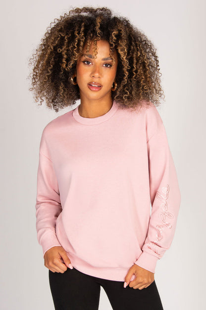 Woman wearing a pink sweatshirt against a plain background
