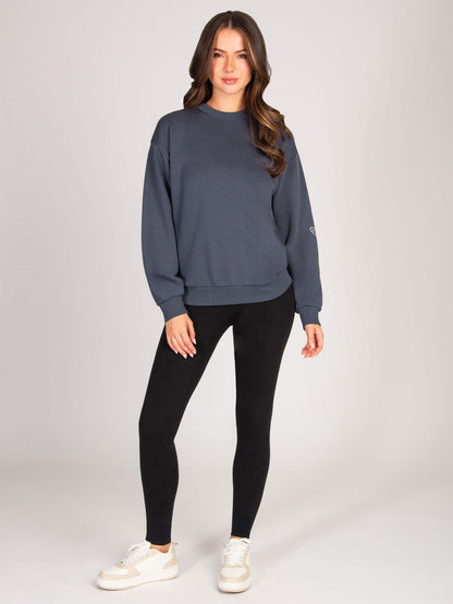 Woman wearing a gray sweatshirt and black leggings on a white background