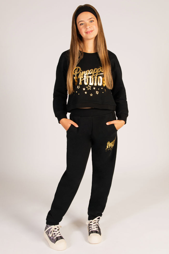 Teen's gold and black sweatshirt decorated with gold festive stars and Pineapple Dance Studios logo