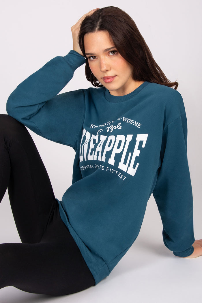 Woman wearing a teal sweatshirt with 'Pineapple' text on a white background