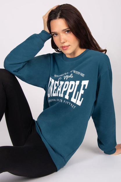 Woman wearing a teal sweatshirt with 'Pineapple' text on a white background